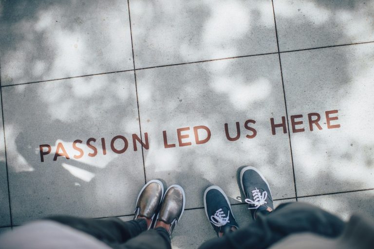 passion led us here Schriftzug "Passion led us here" auf dem Boden, mit zwei Paar Schuhen darüber.