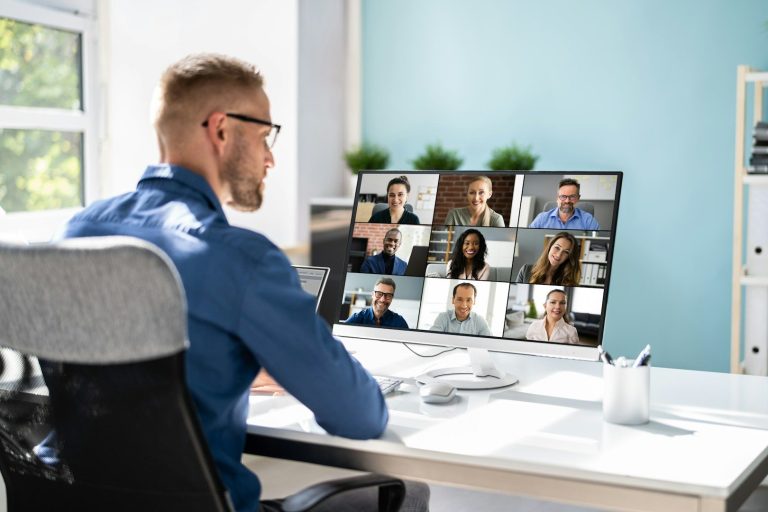 Online-Format Mann sitzt vor einem Computer mit mehreren Videoanrufen auf dem Bildschirm.